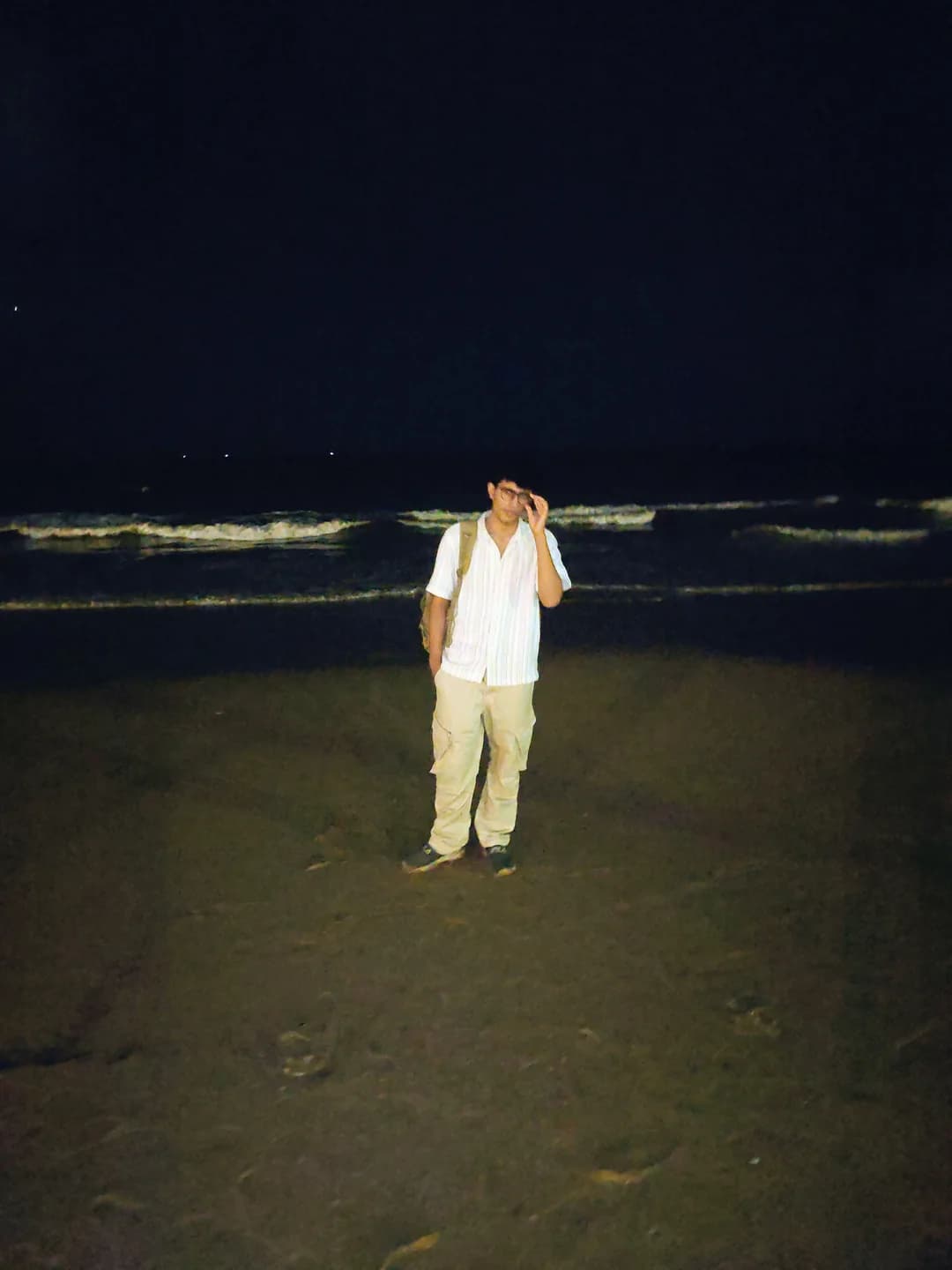 Aarush standing on a beach at night with waves behind him.