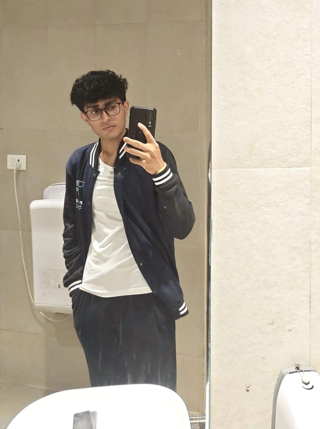Aarush in a black jacket, photographed in a full-length mirror.