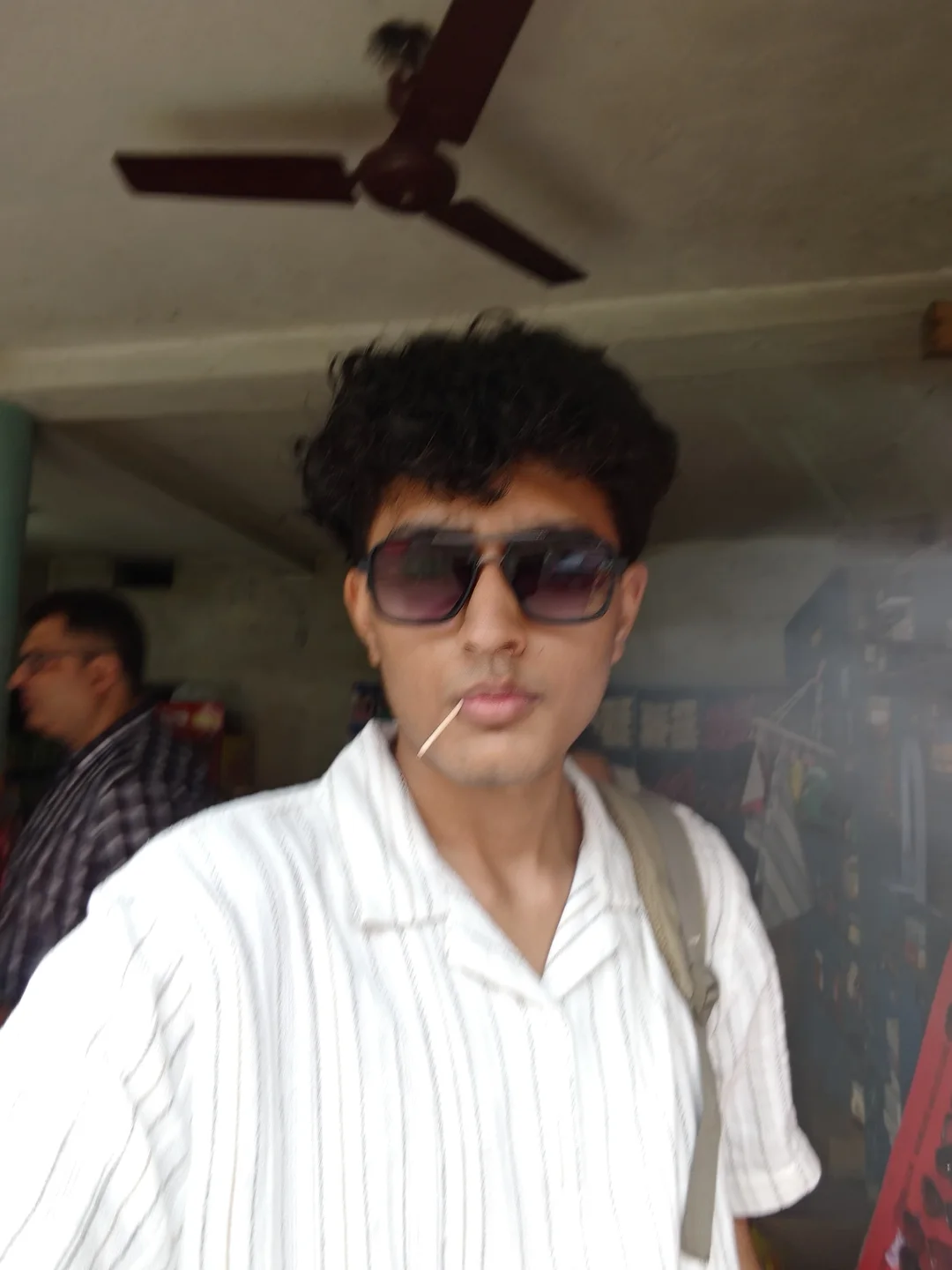 Aarush wearing sunglasses and a white striped shirt.