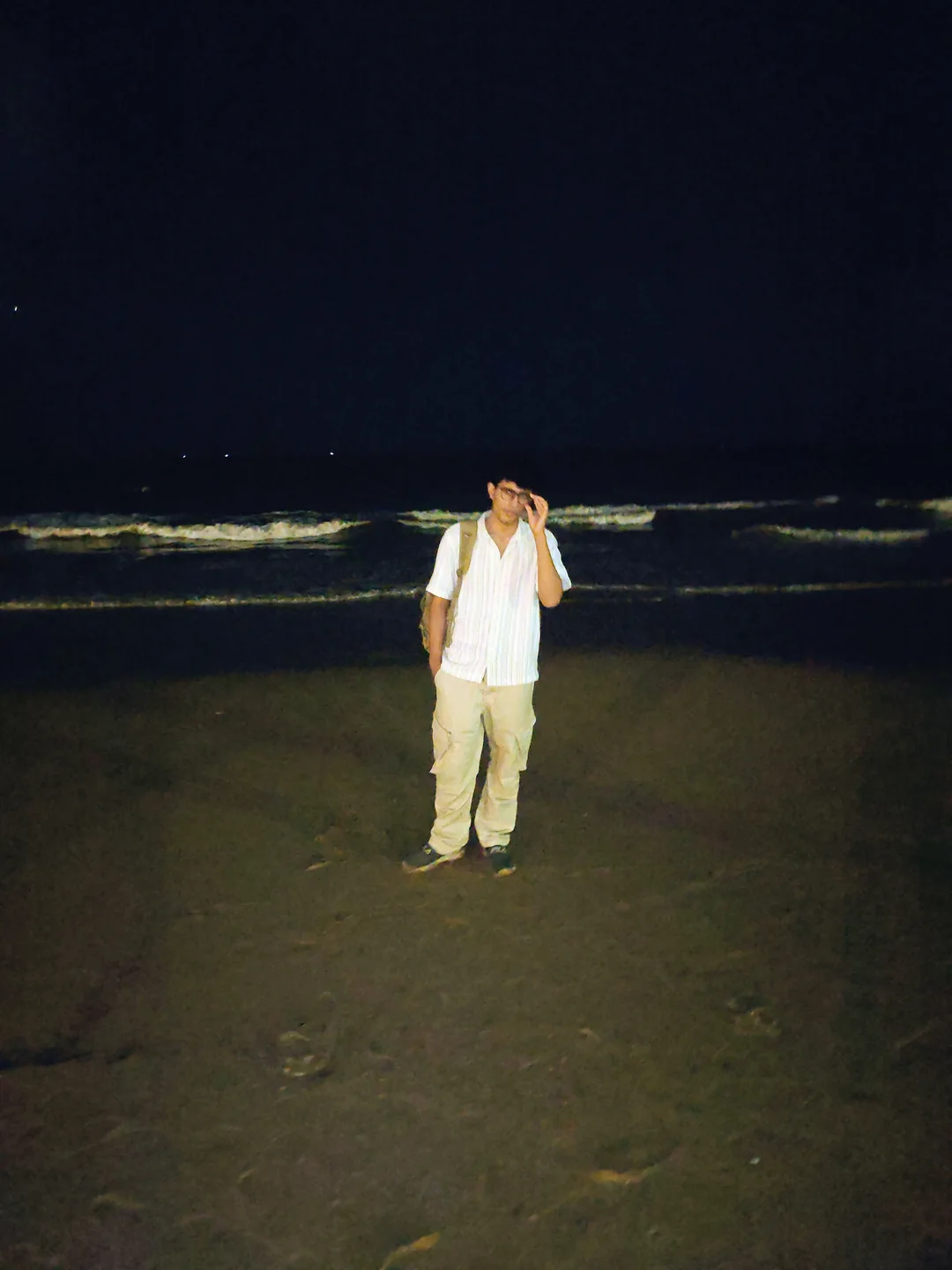 Aarush standing on a beach at night with waves behind him.